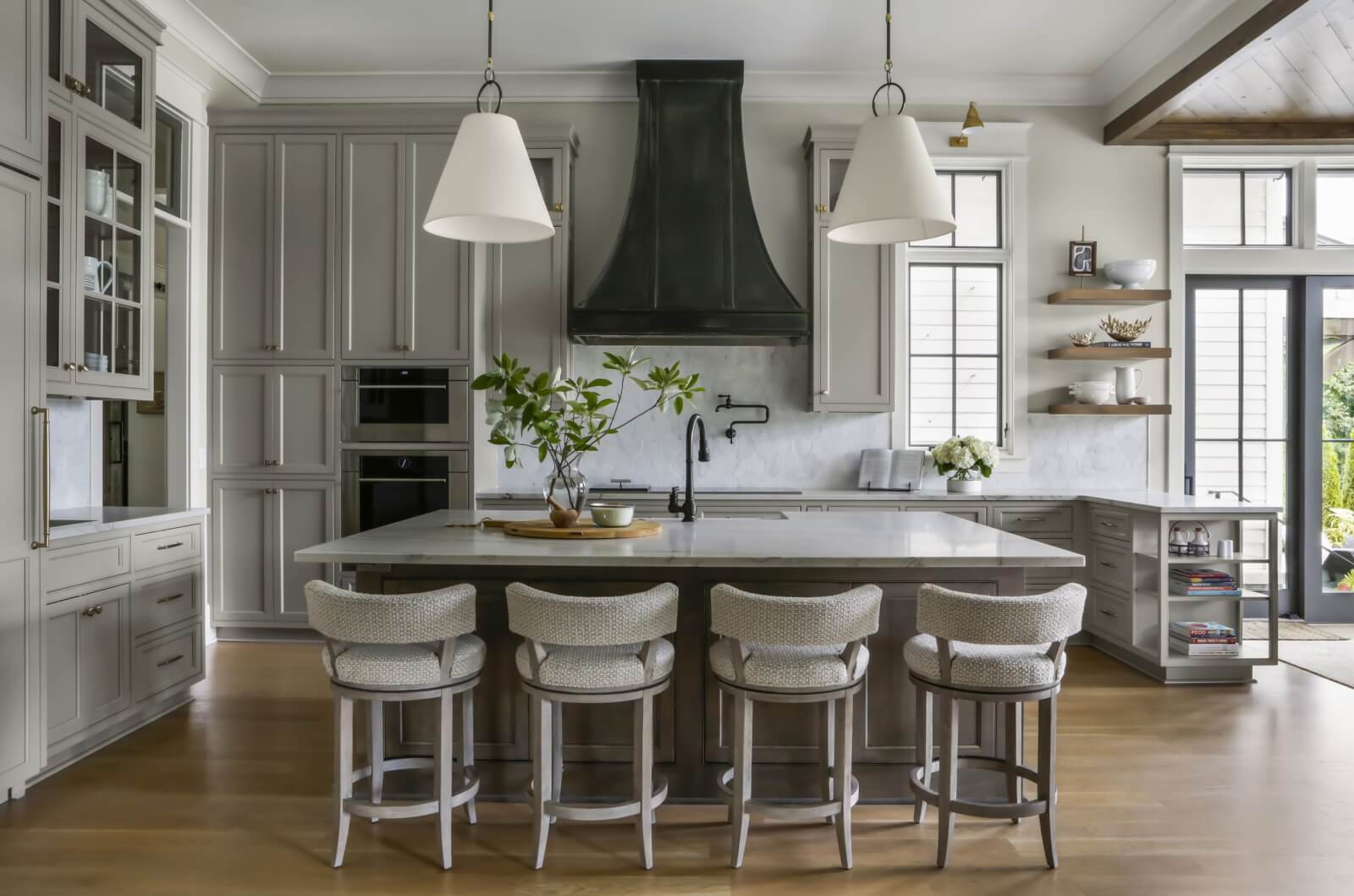 Kitchen with light gray cabinetry and a kitchen island with four stools.