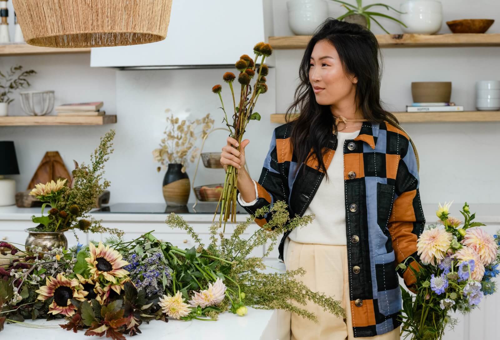 Woman holding flowers, wearing a quilted chore jacket.