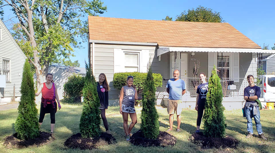 A group of volunteers posing outside in front of a home.