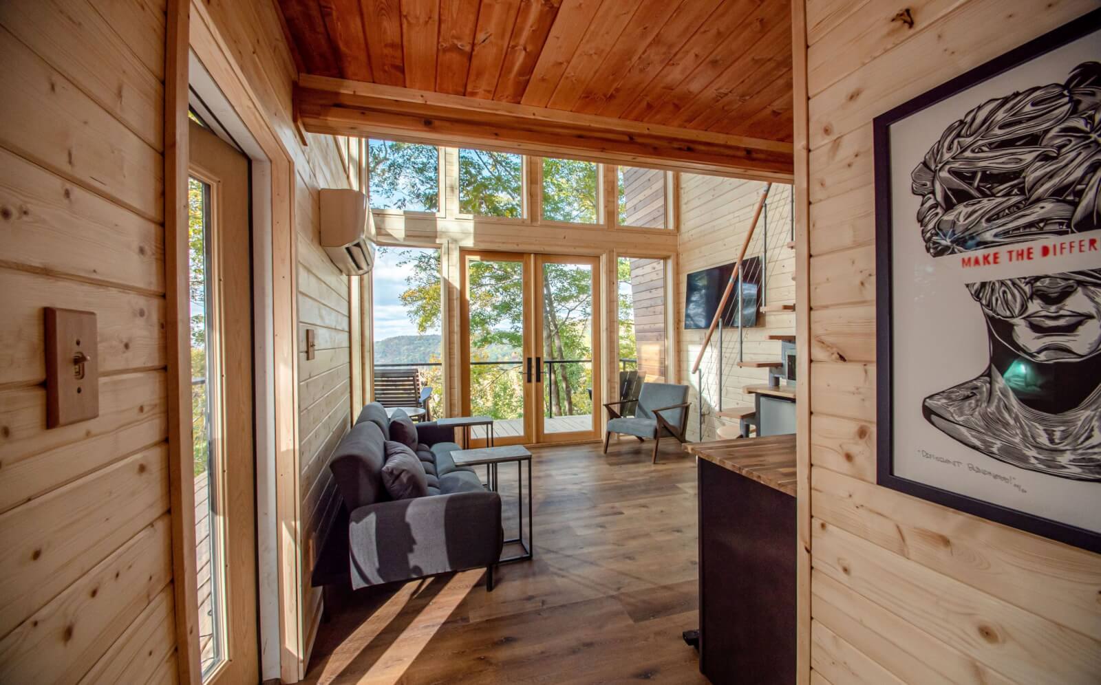 Living room area with wood walls and two-story windows.