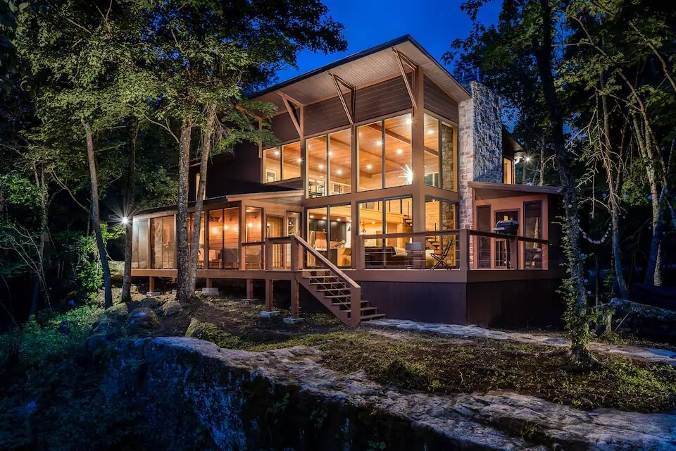 Nighttime view of two-story luxury cabin in the woods.