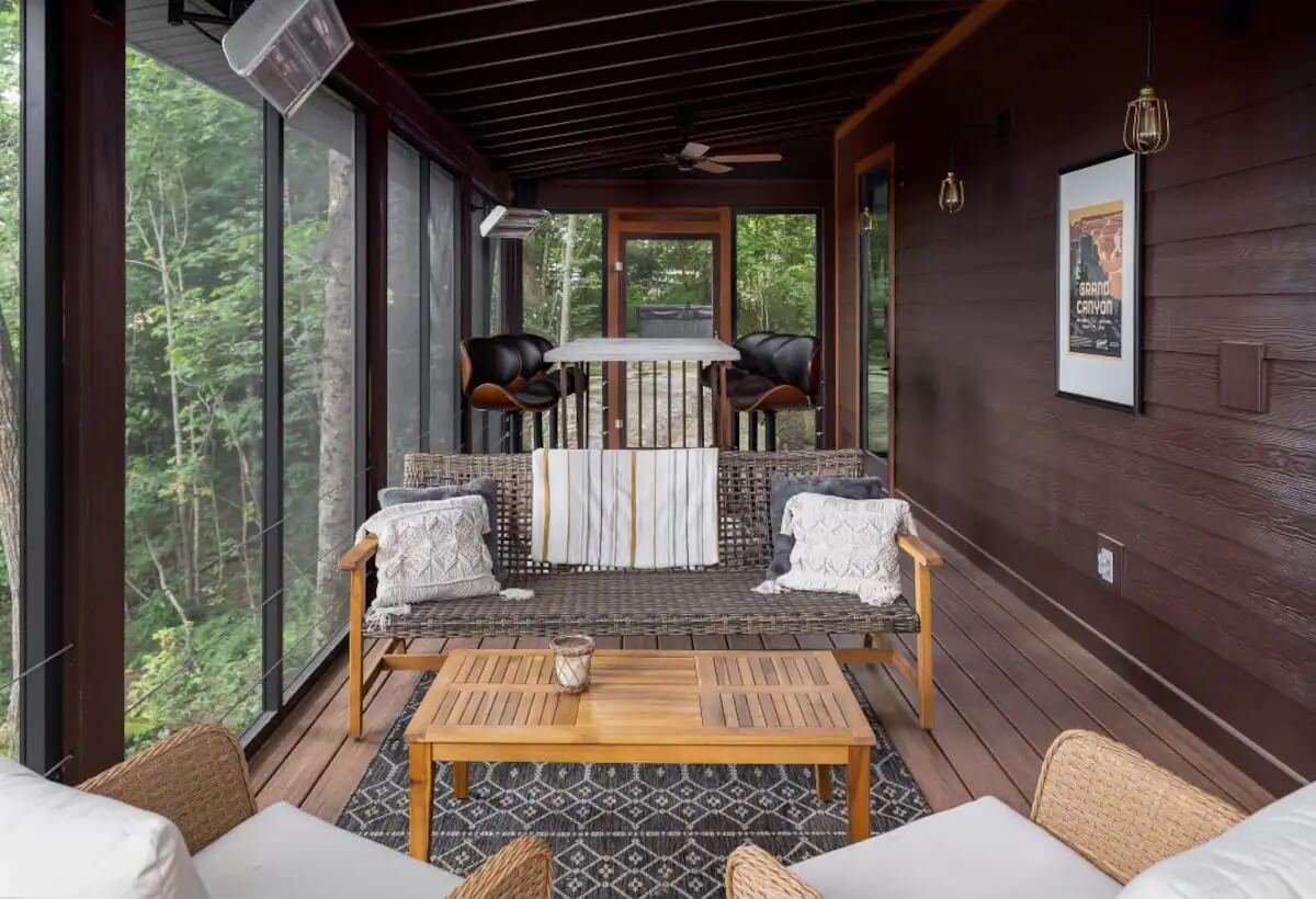 Covered porch with dining table, couch, and chairs.