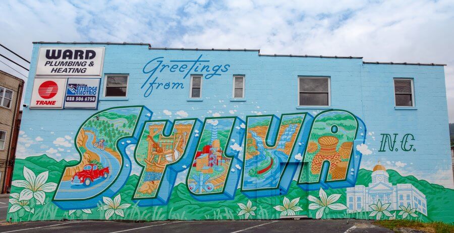 Colorful mural on side of a wall that reads Greetings From Sylva