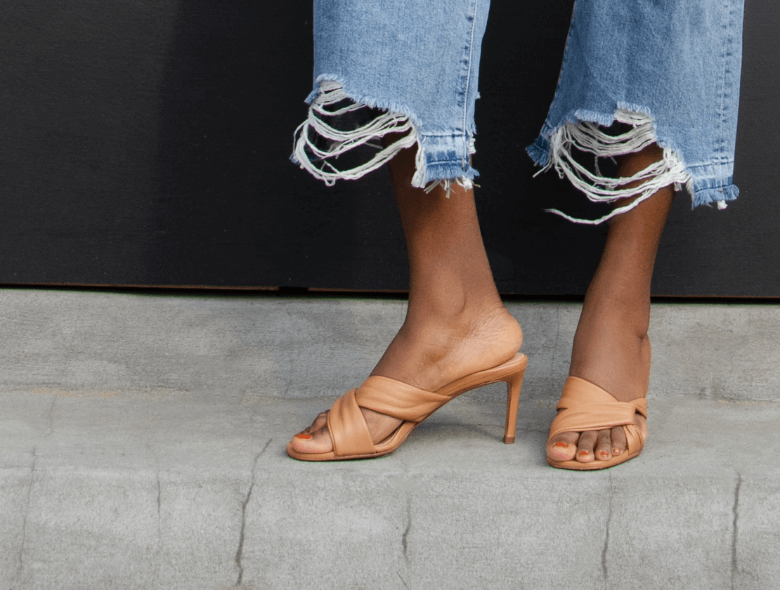 Woman wearing distressed jeans with tan cross strap heels