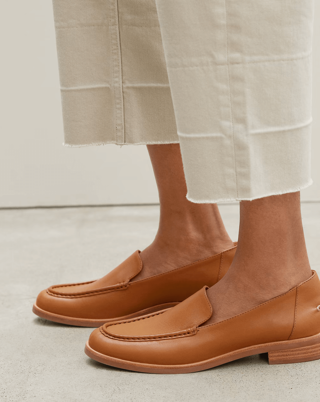 Woman wearing white pants and Everlane brown modern loafers.