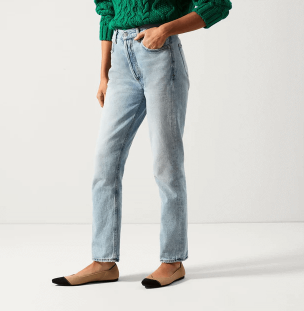 Woman wearing green sweater, jeans and tan and black Rothy's pointed flats